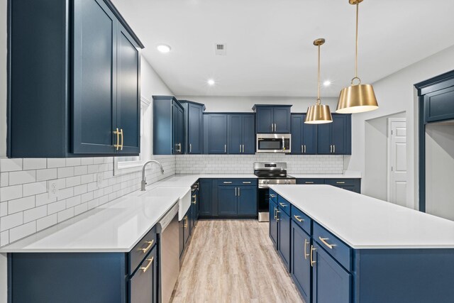 kitchen with blue cabinets, light hardwood / wood-style floors, decorative light fixtures, decorative backsplash, and appliances with stainless steel finishes