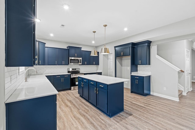 kitchen featuring light wood-type flooring, stainless steel appliances, sink, a center island, and hanging light fixtures