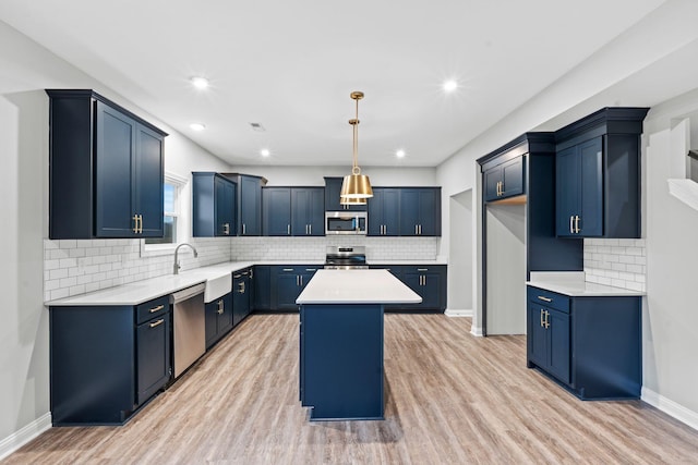 kitchen featuring light wood-type flooring, stainless steel appliances, blue cabinetry, pendant lighting, and a center island