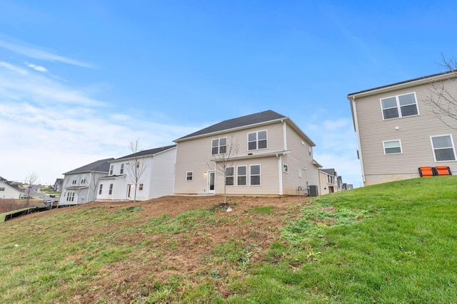 rear view of house featuring a lawn and central AC