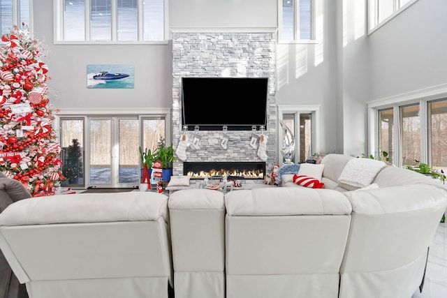 living room featuring a fireplace, a towering ceiling, and a wealth of natural light