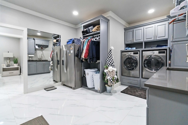 clothes washing area with washing machine and clothes dryer, sink, cabinets, and ornamental molding