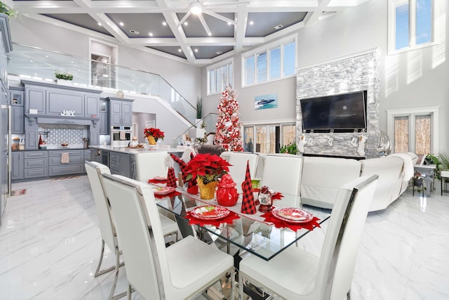 dining room with beam ceiling, a towering ceiling, and coffered ceiling