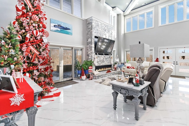 living room with a fireplace, french doors, and a towering ceiling