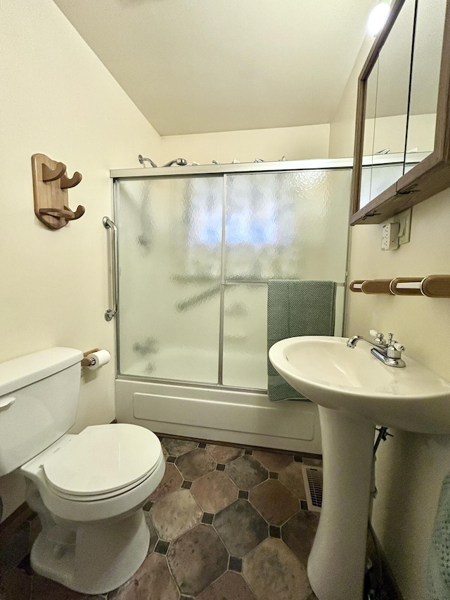 bathroom with bath / shower combo with glass door and toilet