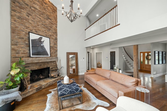 living room featuring a stone fireplace, a notable chandelier, a high ceiling, and hardwood / wood-style flooring