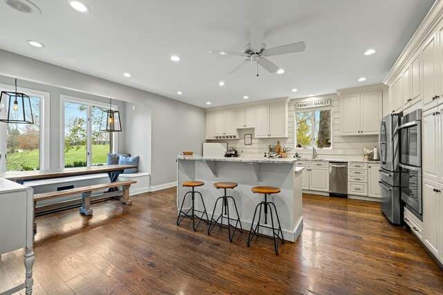 kitchen featuring light stone counters, dark hardwood / wood-style flooring, pendant lighting, decorative backsplash, and white cabinets