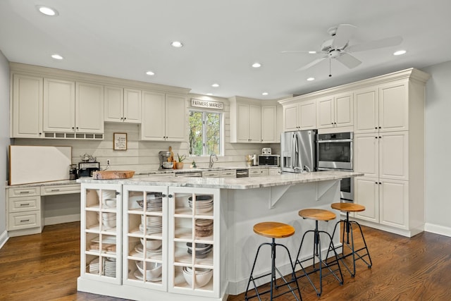 kitchen featuring a kitchen breakfast bar, a spacious island, decorative backsplash, appliances with stainless steel finishes, and dark hardwood / wood-style flooring