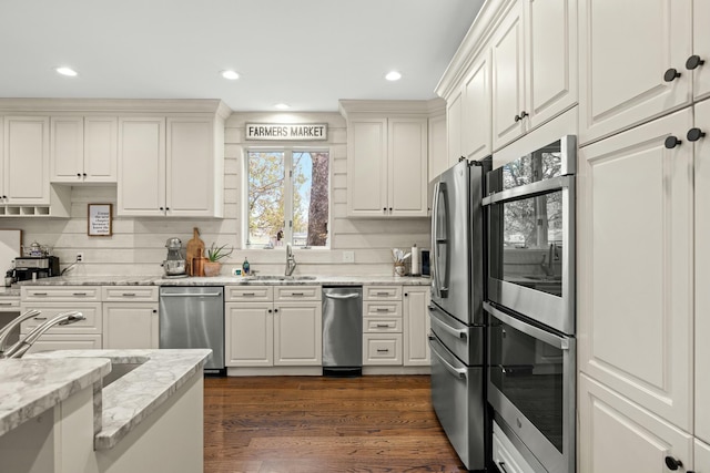 kitchen featuring dark wood-type flooring, sink, light stone counters, white cabinetry, and stainless steel appliances