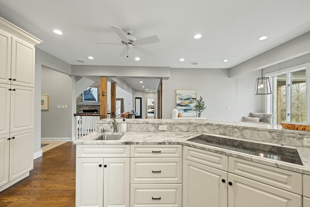 kitchen featuring ceiling fan, sink, light stone countertops, dark hardwood / wood-style flooring, and black electric stovetop