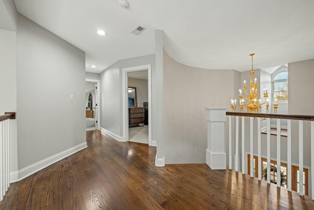 hall with dark wood-type flooring and a chandelier