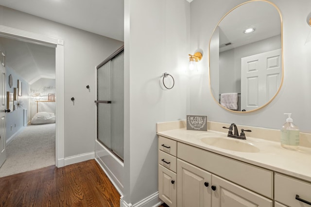 bathroom with hardwood / wood-style floors, vanity, lofted ceiling, and combined bath / shower with glass door