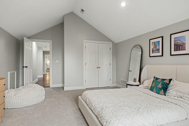 bedroom featuring a closet, light colored carpet, and lofted ceiling