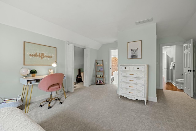 carpeted bedroom with ensuite bathroom and vaulted ceiling