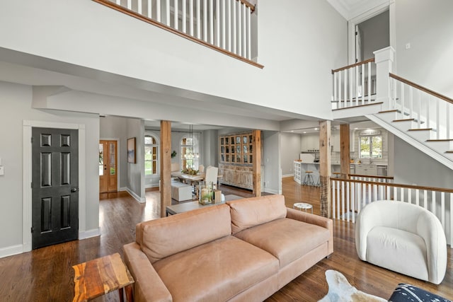 living room featuring crown molding, dark hardwood / wood-style flooring, a towering ceiling, and a chandelier