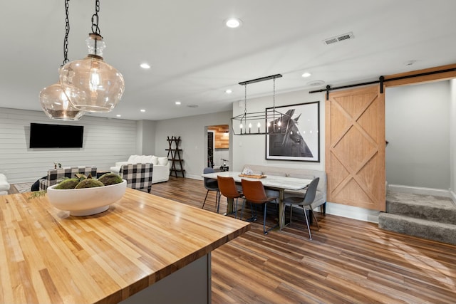 dining room featuring hardwood / wood-style floors, a barn door, and wood walls