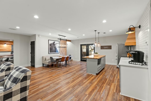 kitchen featuring french doors, stainless steel fridge, pendant lighting, a kitchen island, and hardwood / wood-style flooring