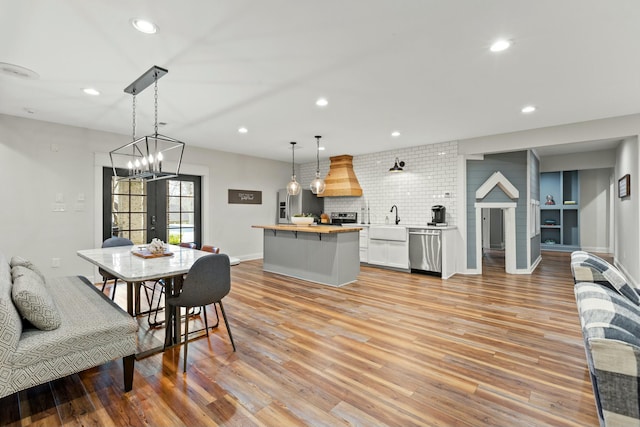 dining space featuring french doors, an inviting chandelier, light hardwood / wood-style flooring, and sink