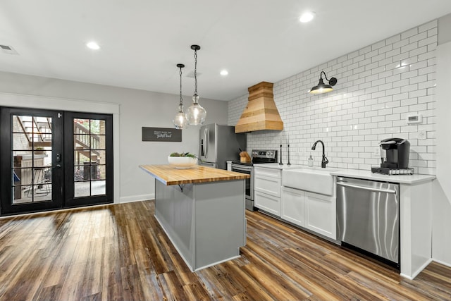 kitchen featuring a center island, wooden counters, white cabinets, sink, and stainless steel appliances