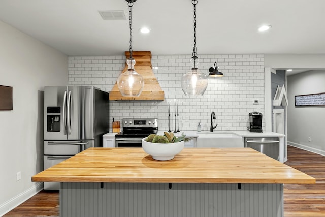 kitchen featuring tasteful backsplash, stainless steel appliances, sink, a kitchen island, and hanging light fixtures