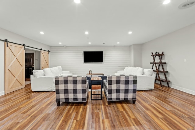 living room with wood-type flooring, a barn door, and wooden walls