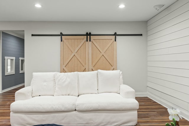 living room with wood walls, dark hardwood / wood-style floors, and a barn door