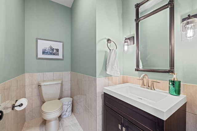 bathroom featuring tile patterned flooring, vanity, toilet, and tile walls