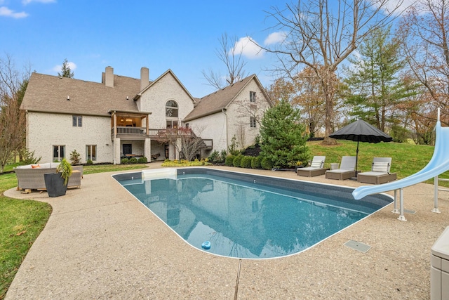 view of swimming pool with a patio area, a yard, and a water slide