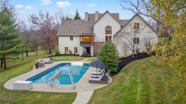 back of property with outdoor lounge area, a balcony, a yard, and a patio