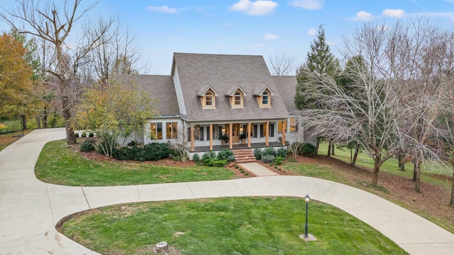 new england style home with covered porch and a front lawn