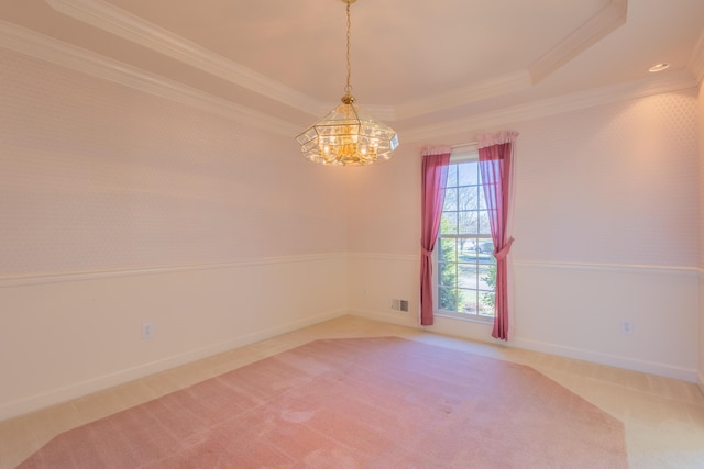 carpeted empty room with a chandelier, ornamental molding, and a tray ceiling