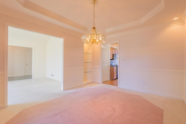 empty room with a tray ceiling, light carpet, a notable chandelier, and ornamental molding