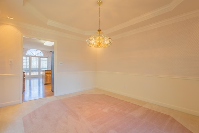 empty room featuring carpet flooring, a notable chandelier, crown molding, and a tray ceiling