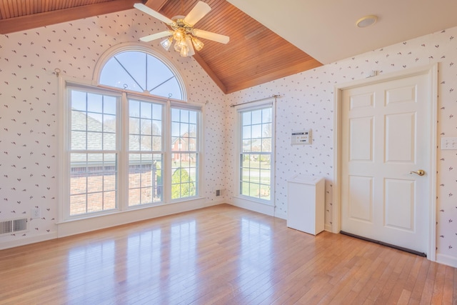 spare room featuring vaulted ceiling with beams, ceiling fan, a wealth of natural light, and light hardwood / wood-style flooring