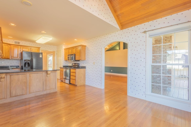 kitchen with light wood-type flooring, appliances with stainless steel finishes, and vaulted ceiling