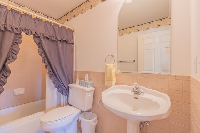 full bathroom featuring sink, toilet, tile walls, and shower / tub combo with curtain