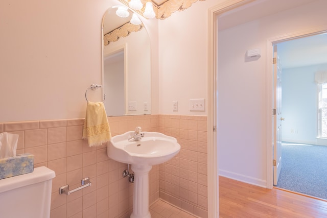 bathroom with hardwood / wood-style floors, toilet, and tile walls