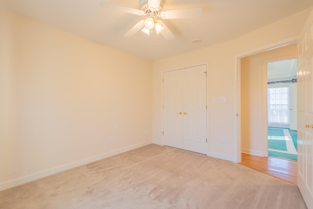 unfurnished bedroom with a closet, light colored carpet, and ceiling fan