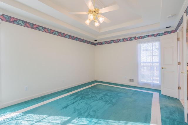 unfurnished room with a raised ceiling, ceiling fan, and carpet