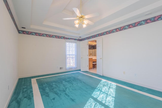 spare room with a raised ceiling, ceiling fan, carpet floors, and ornamental molding