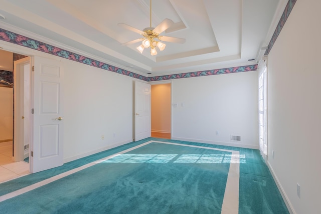 carpeted empty room with ceiling fan and a tray ceiling