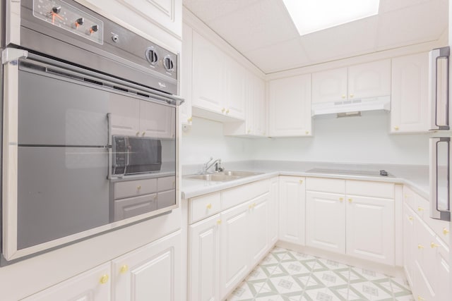 kitchen with white cabinets, stovetop, fridge, and sink