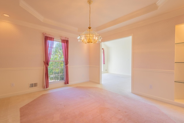 carpeted spare room with a raised ceiling, crown molding, and an inviting chandelier