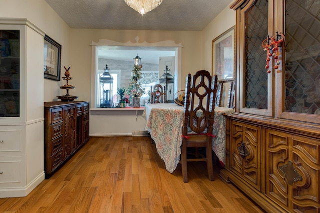 bedroom featuring light hardwood / wood-style floors, a textured ceiling, and a notable chandelier