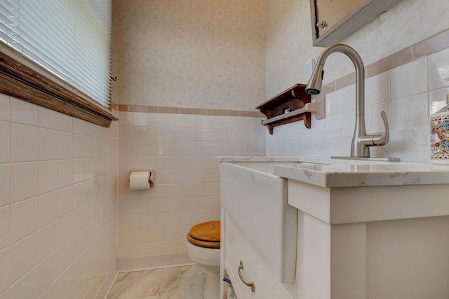 bathroom with vanity, toilet, and tile walls