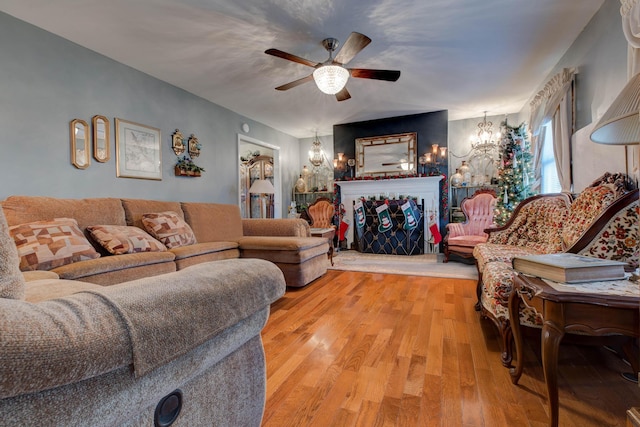 living room with ceiling fan with notable chandelier and light hardwood / wood-style floors