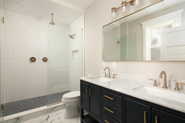 bathroom featuring a tile shower, vanity, and toilet