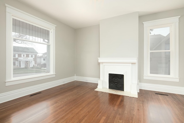 unfurnished living room featuring plenty of natural light and dark wood-type flooring