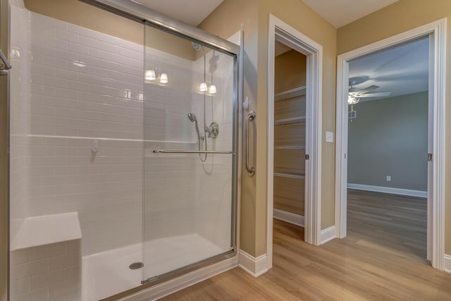 bathroom with wood-type flooring, walk in shower, and ceiling fan