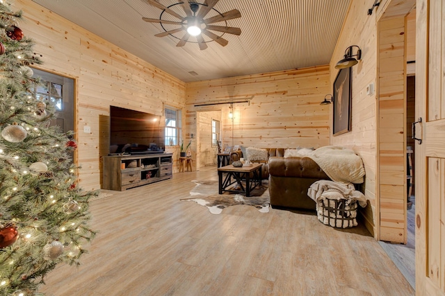 living room featuring ceiling fan, wood walls, and wood-type flooring